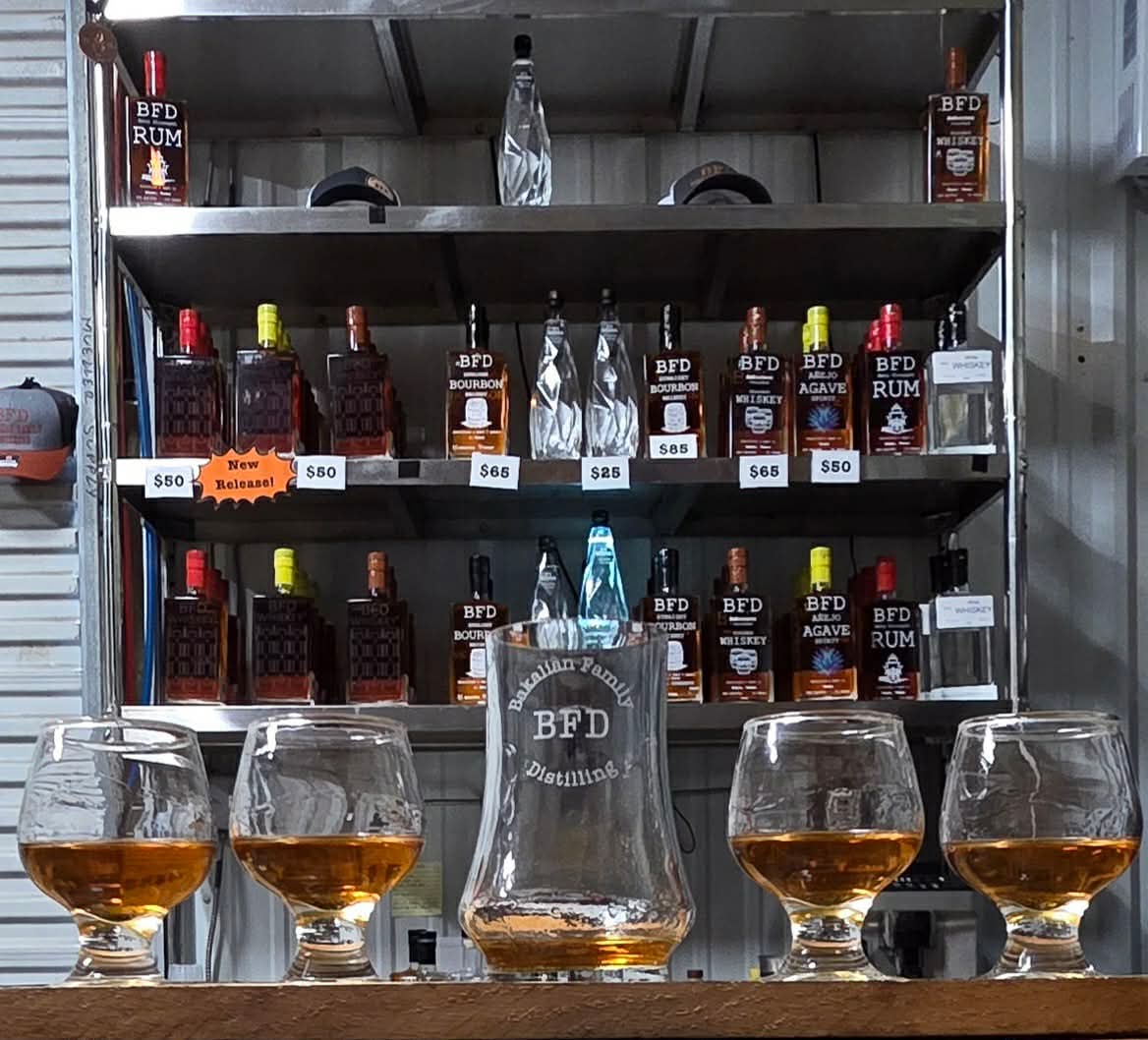 Five BFD tasting glasses in front of the Bakalian Family Distilling spirits display